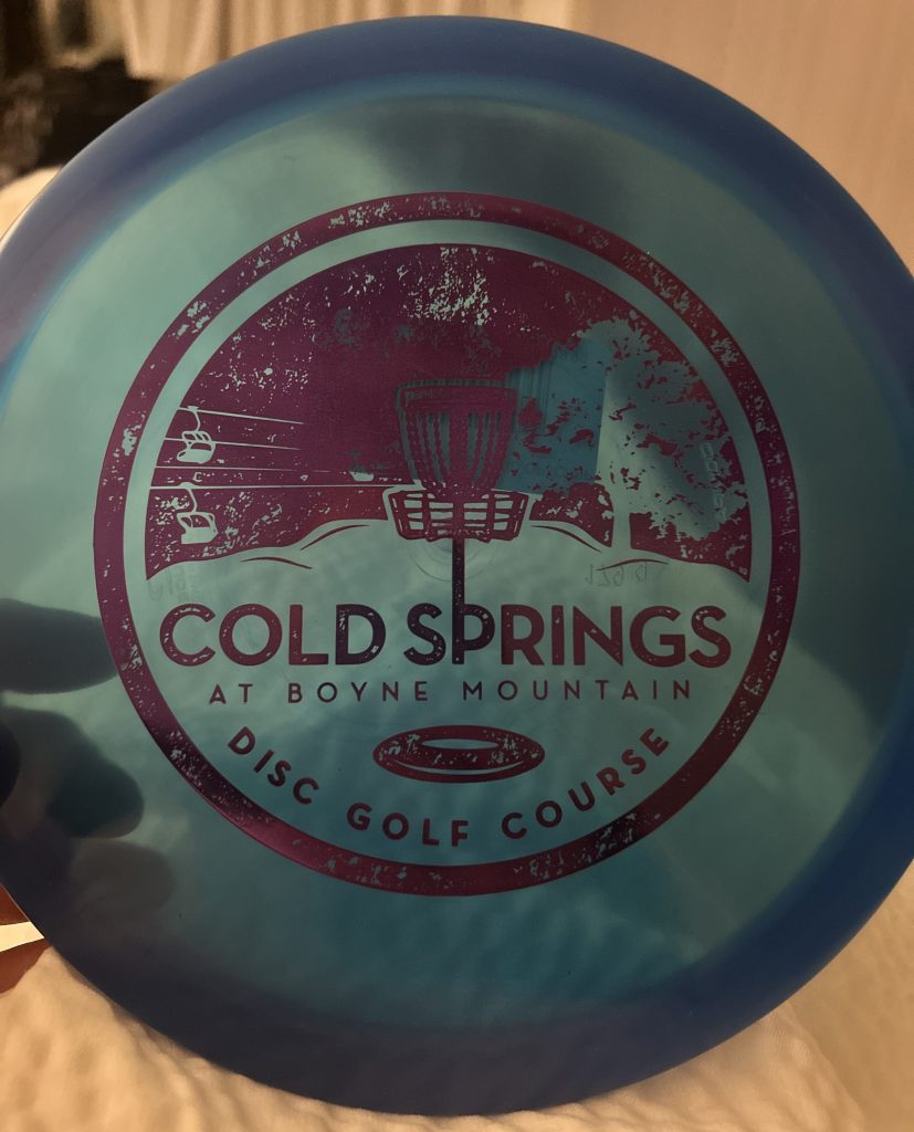 A blue disc with the logo of Cold Springs at Boyne Mountain Disc Golf Course.